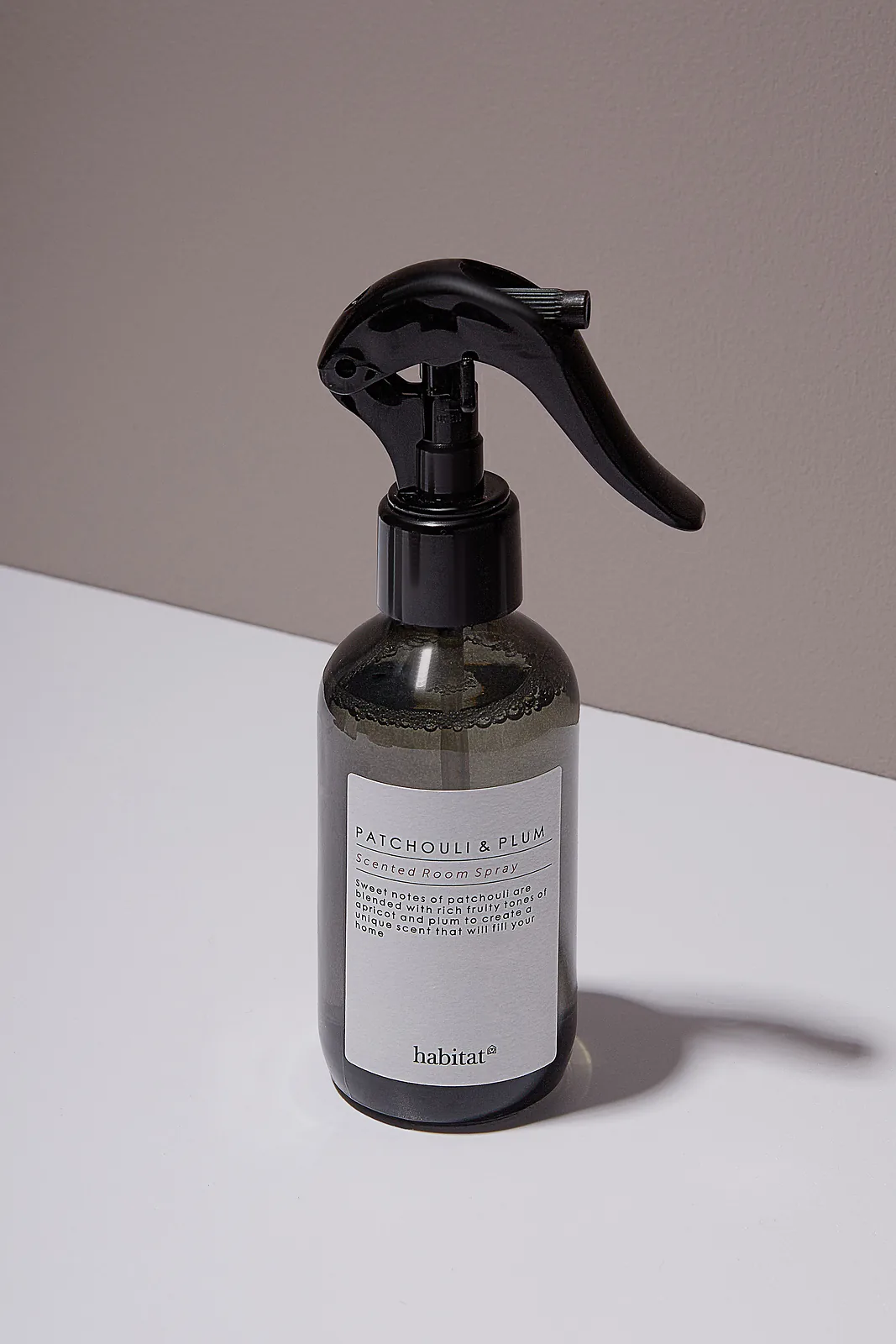 Room spray product photography — dark smoked glass and glossy black trigger