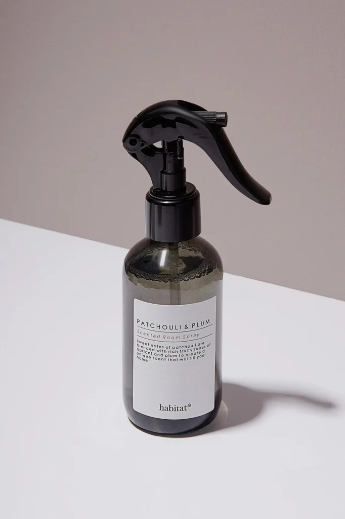 Smoked glass room spray bottle with a black trigger, ecommerce product photo on a white surface with a soft shadow.