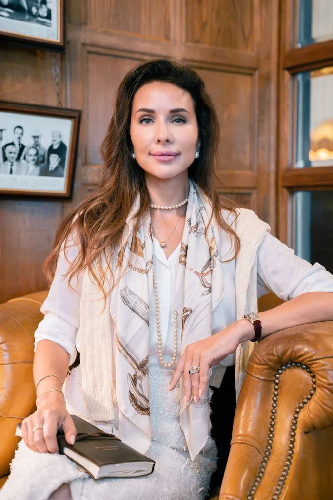 Office headshots Oxfordshire – relaxed executive portrait of a businesswoman seated in a leather armchair in a wood-panelled office.